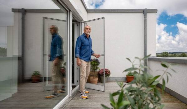 Mann öffnet eine Neher Fliegengitter Drehtür